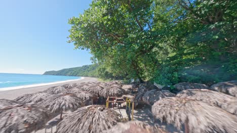 Aerial-flight-over-sunshades-at-sandy-beach-of-San-Rafael-with-resting-tourist-in-Barahona