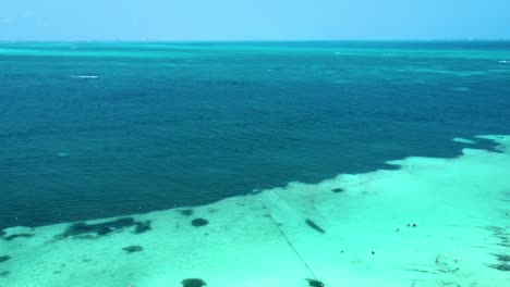 Una-Vista-Aérea-Muestra-Gente-Alegre-Sumergiéndose-En-Las-Aguas-Poco-Profundas-De-Color-Azul-Turquesa-De-Cancún,-México.