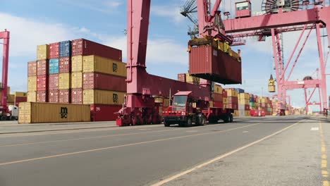 Crane-loading-heavy-shipping-container-onto-cargo-haulage-truck-in-Port-of-Montreal-dockyard