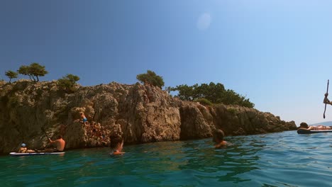 Kroatien,-Krk,-Stara-Baška,-Strand-Von-Zala-Kinder-Klettern-Und-Springen-Vom-Rand-Der-Klippe-Ins-Meer