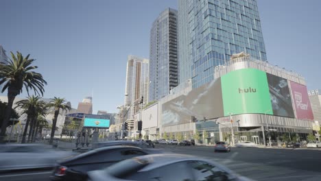 Motion-lapse-of-big-large-LED-Billboard-walls-in-downtown-Los-Angeles-california-showing-marketing-ads-along-car-traffic-and-traffic-lights-at-day-time