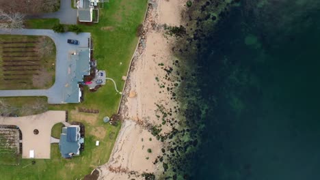 An-aerial,-top-down-view-of-the-waterfront-properties-and-beach-of-the-Long-Island-Sound-in-Greenport,-NY-on-a-sunny-day