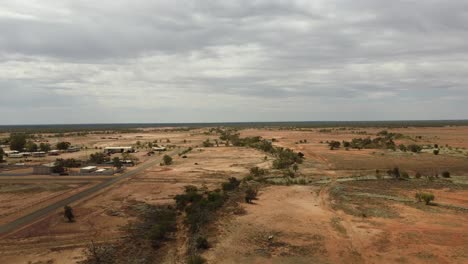 Drone-Ascendiendo-Sobre-Un-Paisaje-Desierto-Que-Muestra-Una-Pequeña-Ciudad-Del-Interior-De-Australia