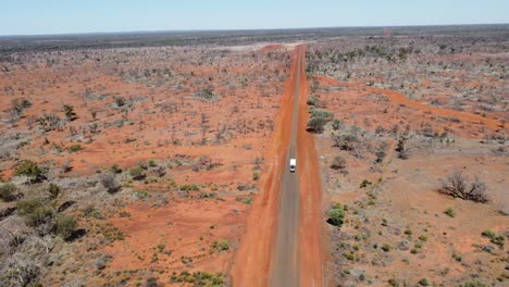 Vista-Aérea-De-Una-Carretera-Rural-Sellada-Mientras-Un-Coche-Remolca-Una-Caravana-Pasando-Por-El-Interior-De-Australia