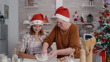 Gradma-with-granddaughter-mixing-ingredients-egg-with-flour-preparing-homemade-traditional-dough