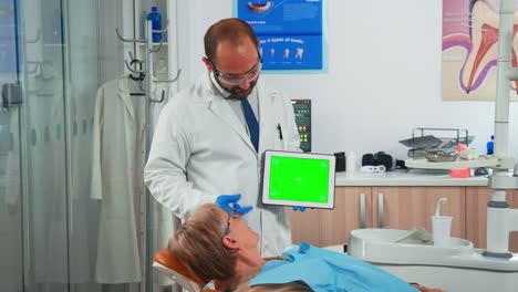 Stomatologist-looking-at-green-screen-tablet