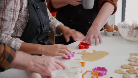 Grandchild-using-cookies-shape-making-traditional-gingerbread-dough-preparing-dessert