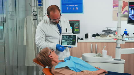 Orthodontist-in-gloves-holding-tablet-suggesting-treatment