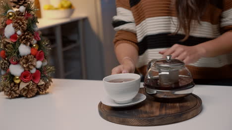 Close-up-of-woman-pouring-tea-from-kettle-at-home