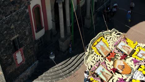 Equipo-De-Hombres-Controlando-Cuerdas-Para-Sostener-Una-Estructura-Gigante-De-Flores-En-La-Catedral-De-Iztapalapa,-Día-De-Muertos,-Conmemoración-Mexicana