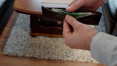 Man-looking-at-Norwegian-banknotes-inside-wallet,-close-up-of-wallet-and-hands