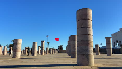 Familia-Marroquí-Disfrutando-De-Los-Pilares-De-La-Torre-Hassan-En-Rabat-Con-La-Bandera-En-El-Fondo