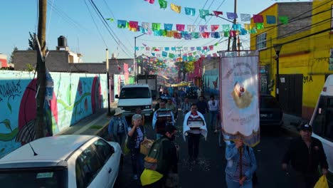 Carnival-procession-in-the-colorful-streets-of-Iztapalapa,-person-throwing-flower-petals---dolly-out