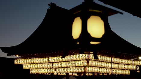 Vista-Borrosa-De-Una-Linterna-Colgante-Iluminada-Con-Una-Toma-De-Fondo-Del-Escenario-Buden-En-Yasaka,-Kyoto-Por-La-Noche