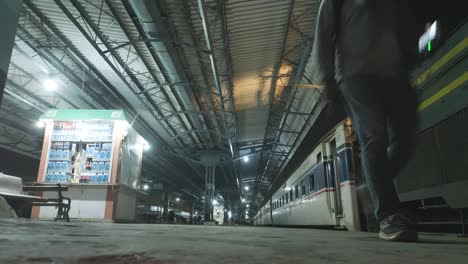 Pakistani-man-dresses-in-light-colours-walking-near-stopped-train-in-Karachi,-Pakistan-train-station