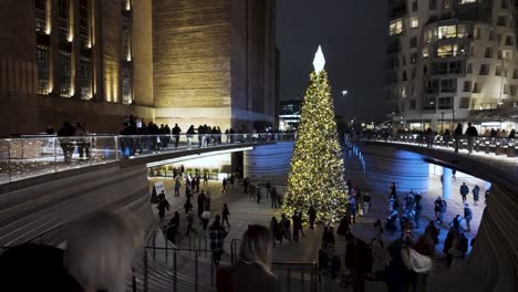 Overlooking-Busy-Crowds-Walking-Past-Illuminated-Festive-Christmas-Tree-At-Battersea-Power-Station