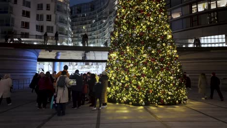 Gruppe-Von-Menschen-Neben-Beleuchtetem-Festlichem-Weihnachtsbaum-Im-Battersea-Kraftwerk