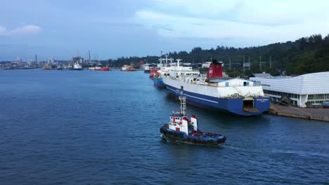 Remolcador-Pasando-Por-Un-Barco-De-Pasajeros-Atracado-En-El-Puerto-De-Balikpapan,-Indonesia