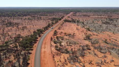 Luftaufnahme-Einer-Befestigten-Landstraße,-Während-Ein-Auto-Einen-Wohnwagen-Schleppt,-Der-Im-Australischen-Outback-Vorbeifährt