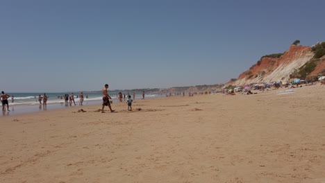 People-walking-and-playing-on-the-beach,-Falèsia,-Algarve,-Portugal