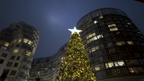 Looking-Up-At-Festive-Illuminated-Christmas-With-Star-On-Top-Outside-Battersea-Power-Station-At-Night-With-Buildings-In-Apartments-In-Background