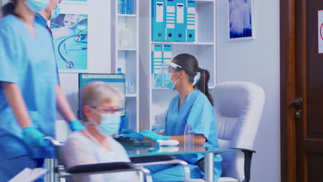 Nurse-at-hospital-reception-greeting-senior-patient