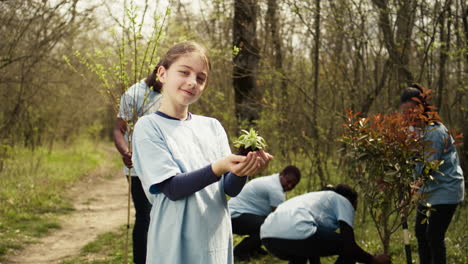 Little-girl-holding-a-small-green-sprout-with-natural-soil