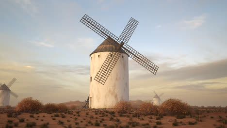 Vintage-agriculture-windmill’s-wings-working-and-rotating-slowly-during-sunset-with-clouds-in-the-background.-Camera-slowly-pans-around-a-building.-Spinning-turbine,-old-technology,-an-energy-exchange