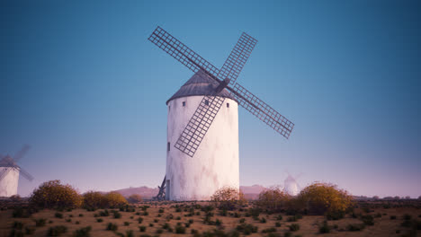 Die-Flügel-Einer-Alten-Landwirtschaftlichen-Windmühle-Arbeiten-Und-Rotieren-Langsam-Bei-Sonnenuntergang-Mit-Wolken-Im-Hintergrund.-Die-Kamera-Schwenkt-Langsam-Um-Ein-Gebäude.-Rotierende-Turbine,-Alte-Technologie,-Ein-Energieaustausch