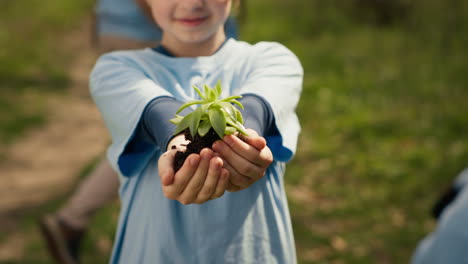 Kleines-Kind-Hält-Erde-Mit-Einem-Grünen-Spross-In-Den-Händen