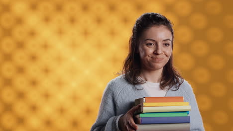 Portrait-of-smiling-woman-holding-stack-of-books,-doing-salutation-hand-gesture