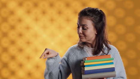 Retrato-De-Una-Mujer-Sonriente-Sosteniendo-Un-Montón-De-Libros-Apuntando-A-Espacios-De-Copia-Vacíos