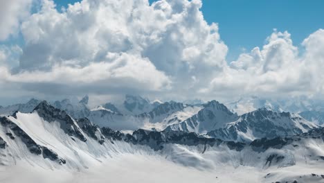 Air-flight-through-mountain-clouds-over-beautiful-snow-capped-peaks-of-mountains-and-glaciers.