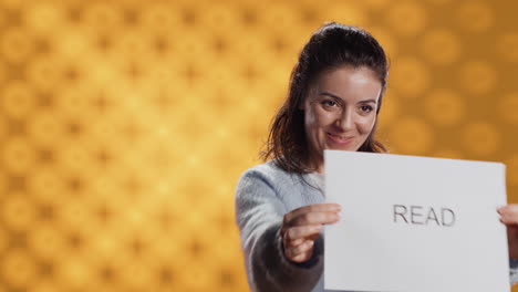 Woman-holding-message-in-hands-urging-people-to-read-more,-studio-background