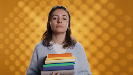 Portrait-of-upbeat-woman-holding-pile-of-books,-studio-background