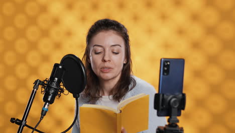 Narrator-looking-at-phone-camera,-filming-herself-reading-book-for-kids