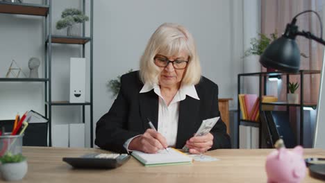 Senior-business-office-woman-accountant-or-banker-using-calculator-making-money-cash-calculations