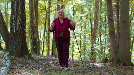 Abuela-Mayor-Caucásica-Excursionista-Turística-Entrenando-Marcha-Nórdica-Con-Bastones-De-Trekking-En-El-Bosque