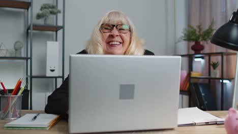 Mujer-De-Negocios-Mayor-Y-Madura-Escondida-Detrás-De-Una-Computadora-Portátil,-Haciendo-Cara-Graciosa,-Bromeando