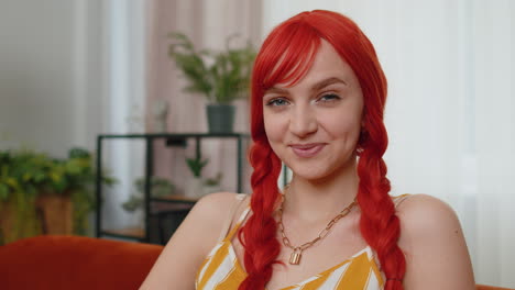 Close-up-of-happy-beautiful-teenager-redhead-ginger-woman-smiling-looking-at-camera-at-home-on-couch