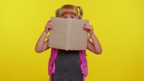 Smiling-schoolgirl-hiding-behind-a-book-laugh-fooling-around-making-playful-silly-facial-expressions