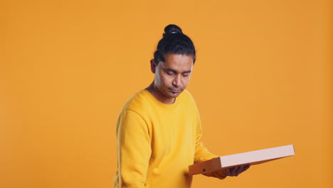 Portrait-of-courier-carrying-stack-of-pizza-boxes,-studio-background