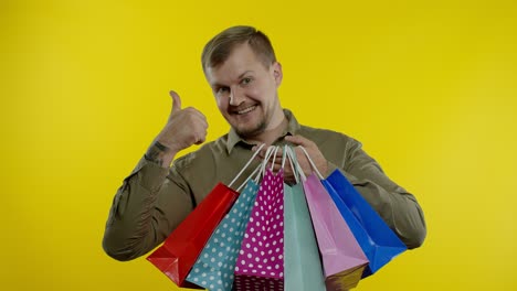 Man-showing-Black-Friday-inscription-on-shopping-bags,-smiling,-satisfied-with-low-prices-purchases