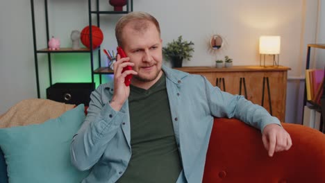 Adult-caucasian-man-enjoying-talking-on-mobile-phone,-conversation-with-friends-at-home-on-couch