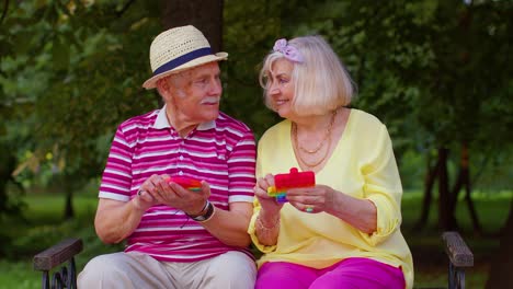 Smiling-senior-old-grandmother-grandfather-playing-anti-stress-touch-screen-push-pop-it-popular-toy