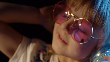 Portrait-of-trendy-stylish-girl-looking-at-camera,-smiling,-child-kid-in-neon-light-at-disco-club