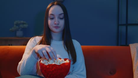 Frau-Sitzt-Allein-Auf-Dem-Sofa,-Isst-Popcorn-Und-Sieht-Sich-Zu-Hause-Eine-Interessante-Fernsehserie-Oder-Einen-Horrorfilm-An