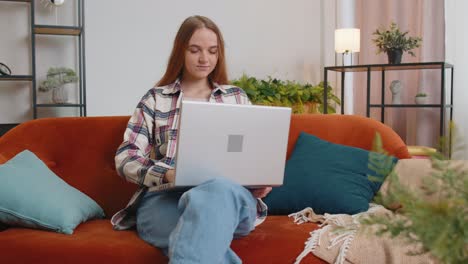 Caucasian-young-woman-sitting-on-sofa-closing-laptop-pc-after-work-online-in-living-room-at-home