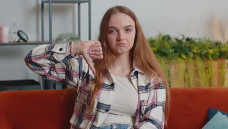 Teen-girl-showing-thumbs-down-sign-gesture,-expressing-discontent,-disapproval,-dissatisfied-dislike