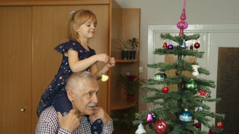 Children-girl-and-elderly-grandpa-decorating-artificial-Christmas-pine-tree-at-old-fashion-room-home